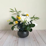 Faux floral arrangement in white, yellow, blue and green