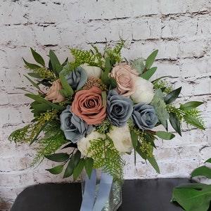 Boho Brides wedding bouquet with dusty rose, dusty blue and white. Roses, peonies and greenery.
