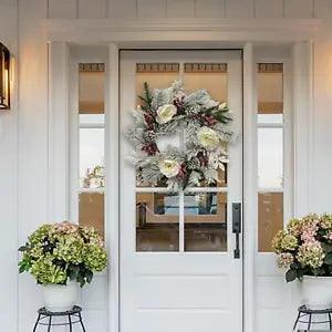 Christmas wreath with white and green foliage, red berries and floral accents for door