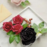 Artificial flower box with burgundy and black foam roses, green leaves in white frame