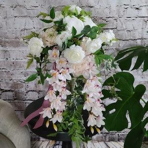 Boho Cascading Wedding Bouquet with Blush Pink and mauve Orchids, blush roses, and white ranunculus with draping greenery.