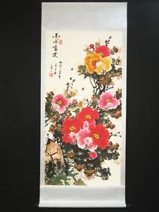 Chinese scroll painting of blooming red and pink peonies with green leaves on a vertical scroll
