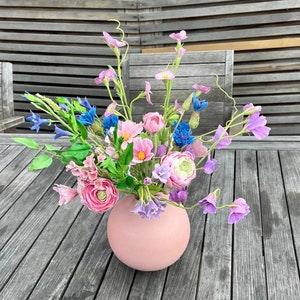 Cold porcelain handmade spring flowers in the pink vase. Wildflowers centerpiece. Cornflowers, cosmos and ranunculus. Realistic flowers