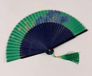 Handheld folding fan with green and dark blue panels and tied ribbon tassel