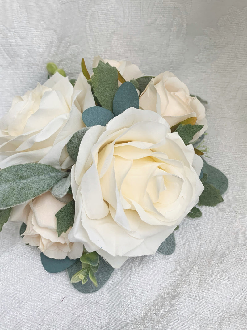 Ivory and white artificial flower cake topper with large rose blooms and green leaves