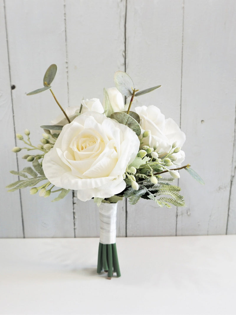 Ivory rose wedding bouquet with lush greenery and white ribbon-wrapped handle