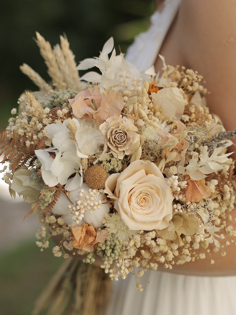 Ivory neutral bridal bouquet with cream roses, hydrangea-like blooms, and dried grasses