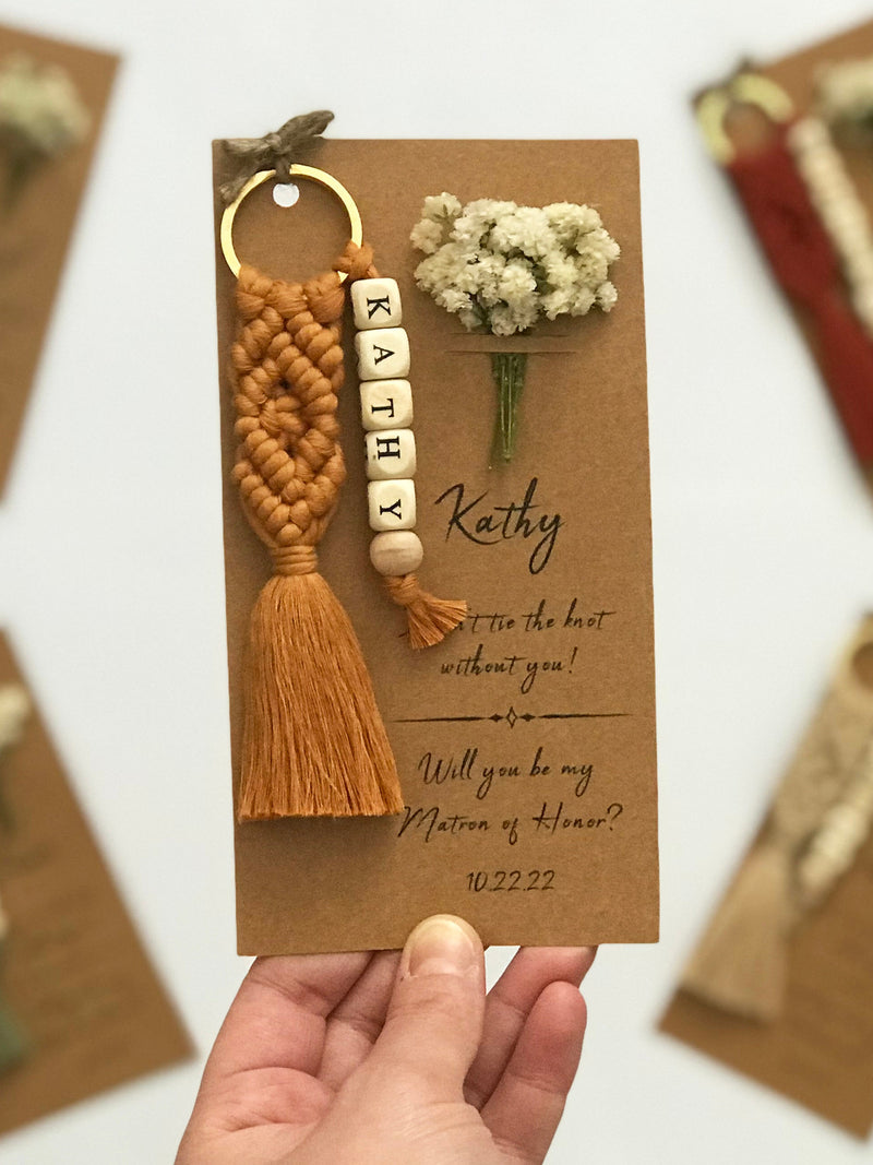 Bridesmaid proposal card with gold ring keychain, tan macrame tassel, and letter beads