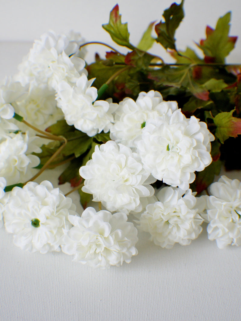Ivory silk zinnia flower bunch with layered blooms and green leaves