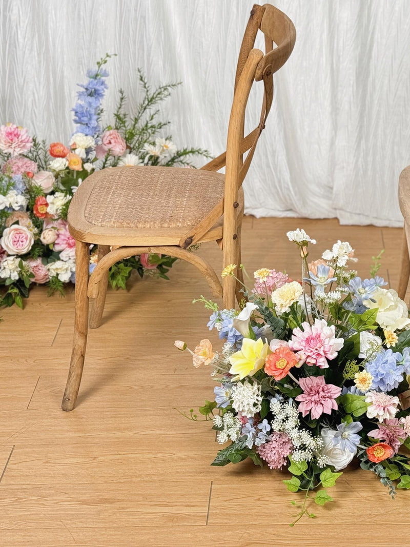Wooden chair with pastel wildflower bouquet arrangement at base