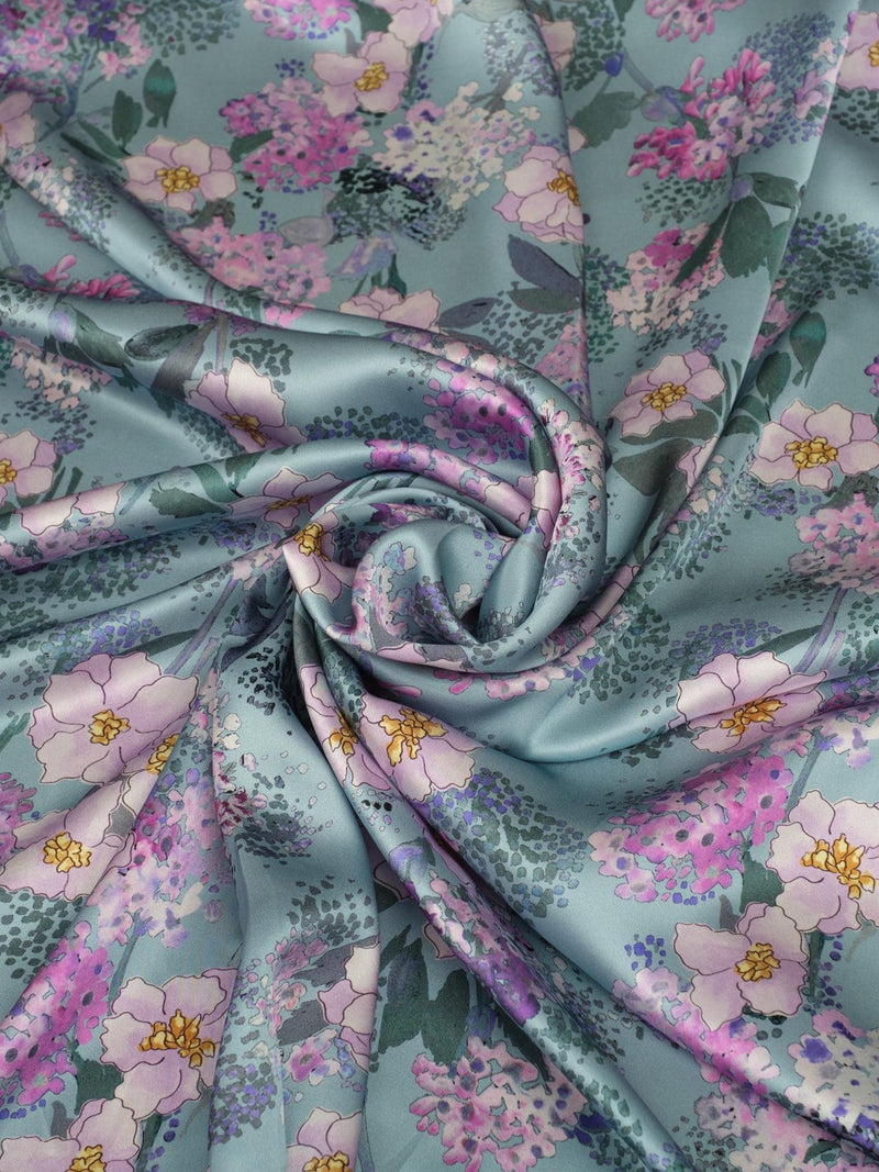 Light blue silk satin fabric with small pink and yellow floral pattern, draped fold