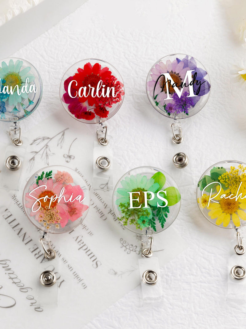 Set of round pressed-flower badge reels with cursive name medallions and silver clips