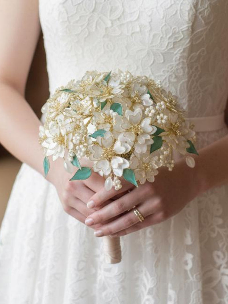 Ivory and gold bridal bouquet with pearl blossoms, green leaf accents, wrapped stems