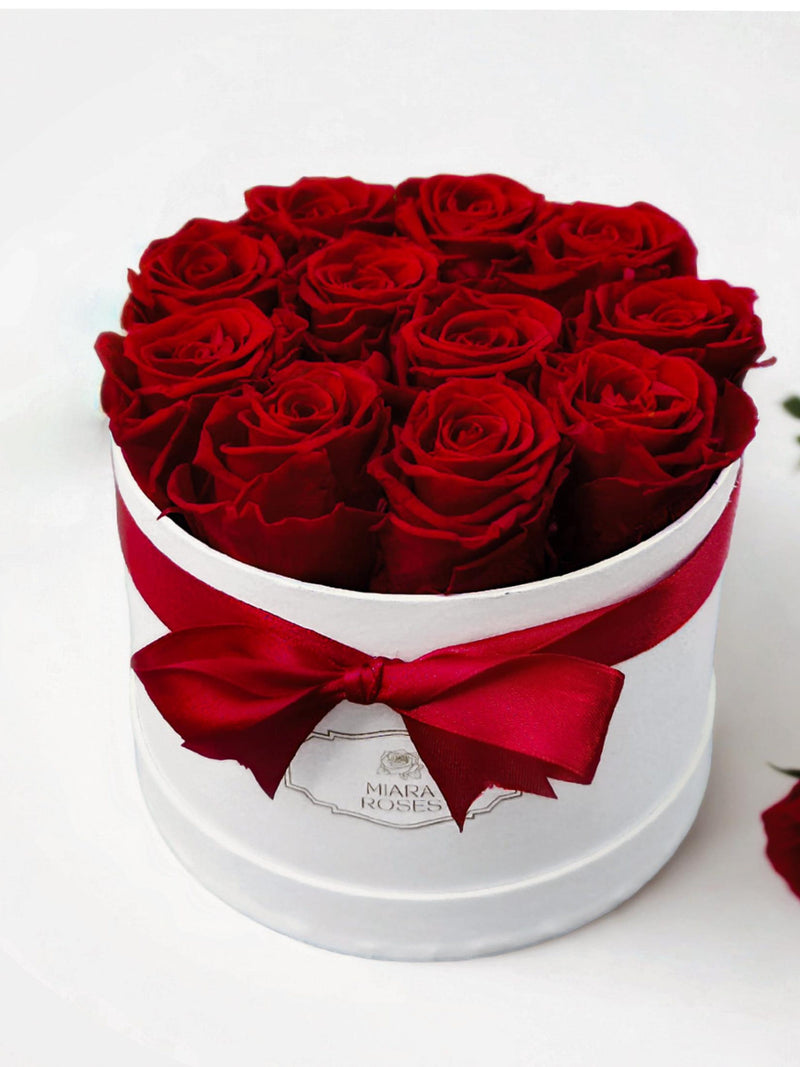 White flower gift box with red preserved roses and red satin bow ribbon