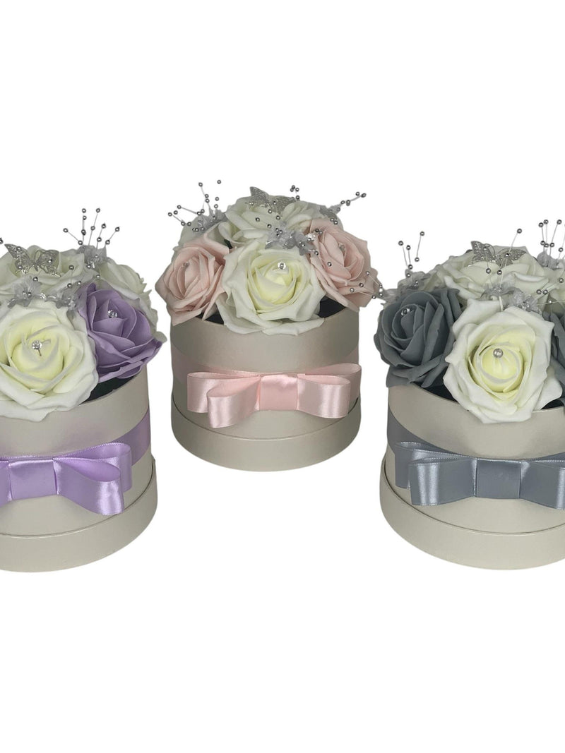 Artificial rose hat box gift set with ribbon bows in pink, lavender, and gray