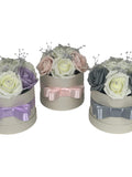 Artificial rose hat box gift set with ribbon bows in pink, lavender, and gray