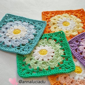 Handmade crochet blanket squares with daisy flower motifs in teal, orange, green, and purple