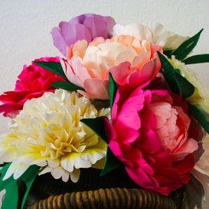 Paper peony flower bouquet with ombre pink, orange, white blooms and green leaves