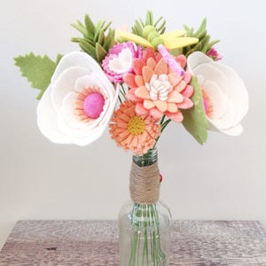Felt flower bouquet with pink, peach, and white blooms and green leaves