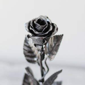 Silver metal rose with curled petals and leaf accents on a slender stem