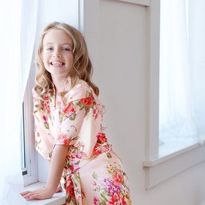 Kids floral satin robe with tie belt, long sleeves, V-neck, worn by a smiling girl