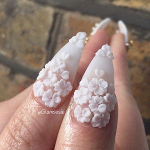 White lace blossom floral appliques, three-petal flower clusters on a finger