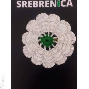 White daisy-like flower brooch with textured petals and a green center