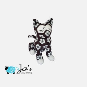 Black crochet cat amigurumi with white floral motifs and patterned paws