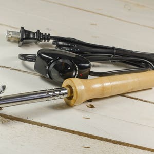 Soldering flower iron tool with wooden handle, metal tip, and black power cord