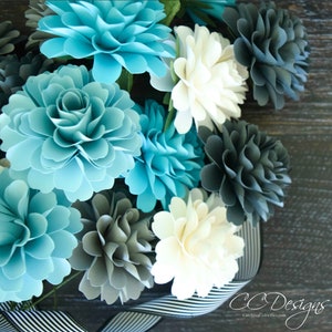 Small paper dahlia flowers in light blue, white, and dark gray, close-up bouquet