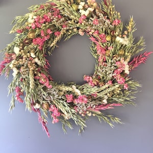 Dried flower wreath with pink and white blossoms and green foliage, round wall decor