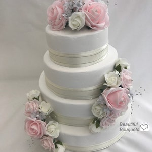Tiered wedding cake topper with pink and white rose clusters on three tiers