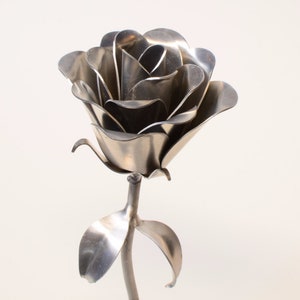 Bare aluminum metal rose sculpture with curved petals on a stem, no engraving visible