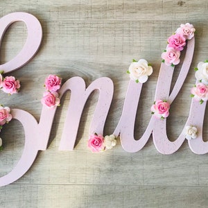 Large wooden cursive name sign with pink and white flower decorations