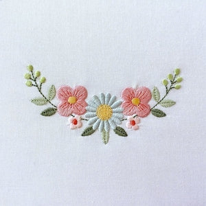 Curved floral embroidery border with pink, yellow, and light blue flowers and green leaves