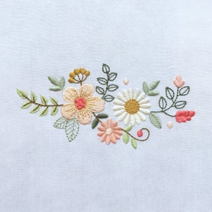 Floral machine embroidery design with daisy, rose and leaves on light fabric