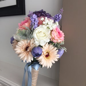 Large wedding bouquet with white rose, pink and purple blooms, blue accents, and satin ribbon wrap