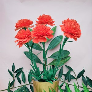 Orange paper carnation bouquet in a pot with green leaves