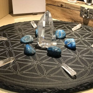 Sacred geometry crystal grid with dark slate circle, clear tower crystal, blue stones