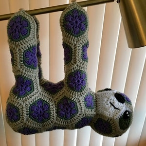 Crocheted sloth plush in light green with purple flower appliques