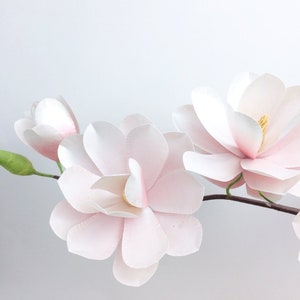 Magnolia paper flower decoration with white and blush pink petals and green leaves