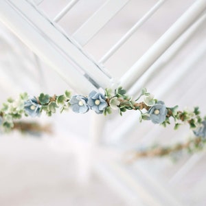 Dainty forget-me-not flower crown with small blue blossoms and green leaves, headband style