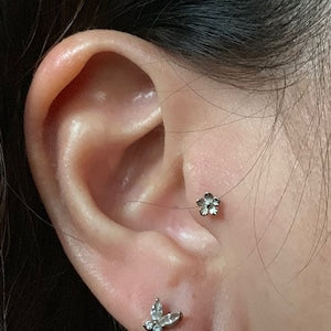 Small flower-shaped stud earring with a dark green center and silver petals