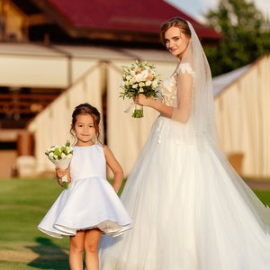 White satin flower girl dress with sleeveless bodice and flared skirt