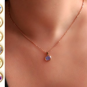 Rose gold flower necklace with small blue pressed-flower resin pendant on a delicate chain