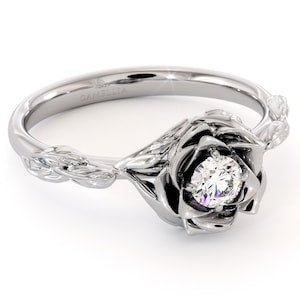 White gold flower-inspired solitaire diamond ring with leaf-style accents