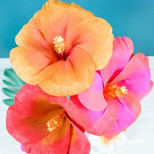 Set of three crepe-style hibiscus paper flowers in orange and pink with yellow centers