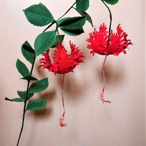 Red hibiscus paper flowers with green leaves on thin stems