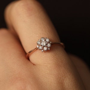 Gold band engagement ring with round flower diamond cluster and small stones