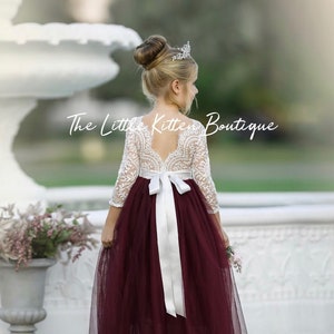 Ivory lace long-sleeve bodice with maroon tulle skirt and white bow sash